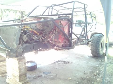 1986 Ford Bronco - A custom-built off-road vehicle, likely a modified 1986 Ford Bronco, is shown with its engine exposed and supported by wooden blocks. The v…
