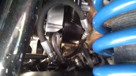 1996 Ford Bronco - This image shows a close-up view of a vehicle's suspension system, featuring a bright blue coil spring and various hydraulic lines and mech…