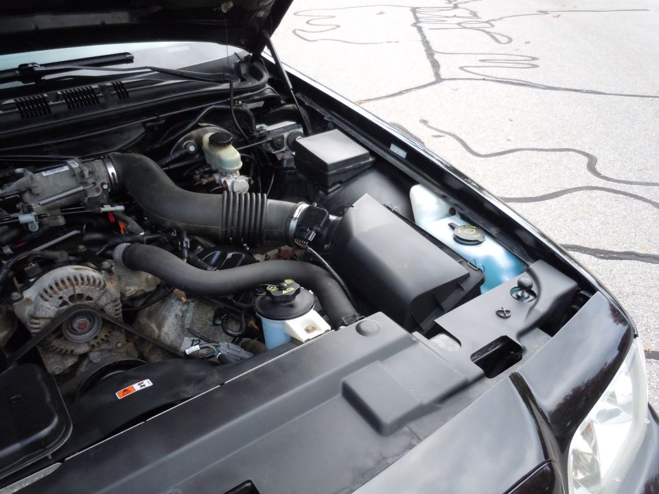 Engine bay of a black 2001 Ford Crown Victoria with hood open.