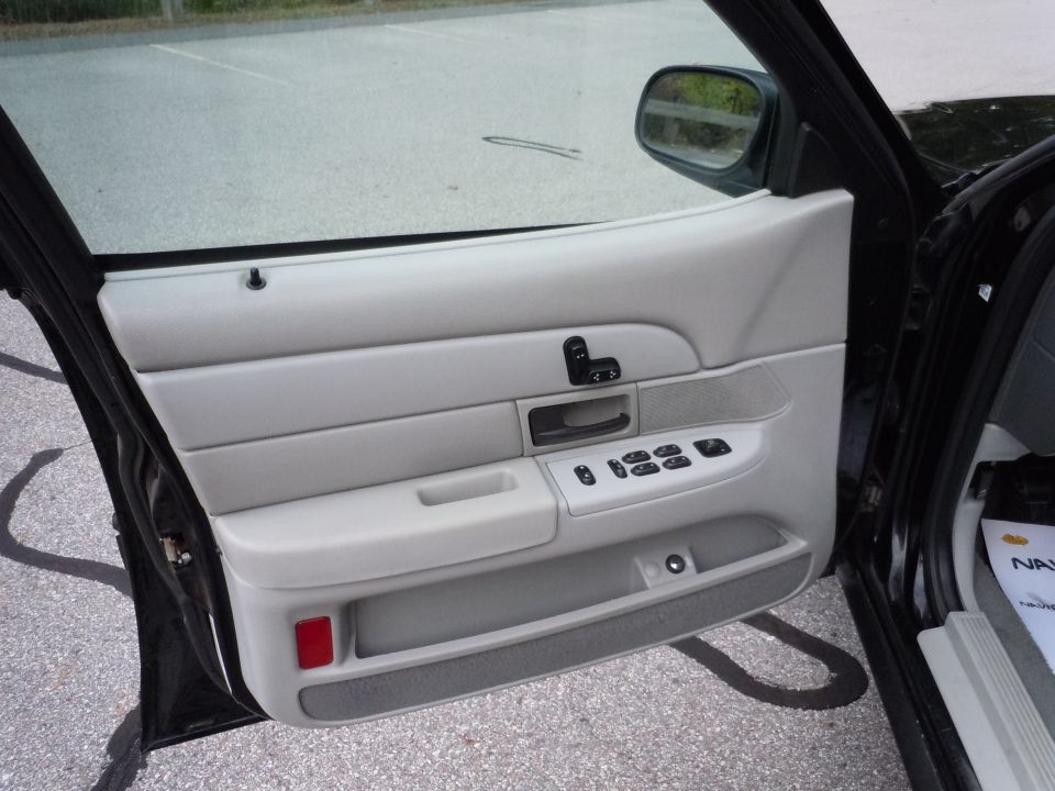 Interior door panel of a black sedan with light gray trim, power window controls, and a red reflector.