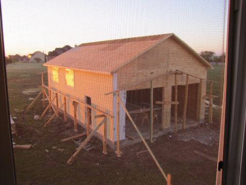 1995 Ford Bronco - A wooden structure, possibly a garage or workshop, is under construction in a grassy field during sunset. The building has a roof and walls…