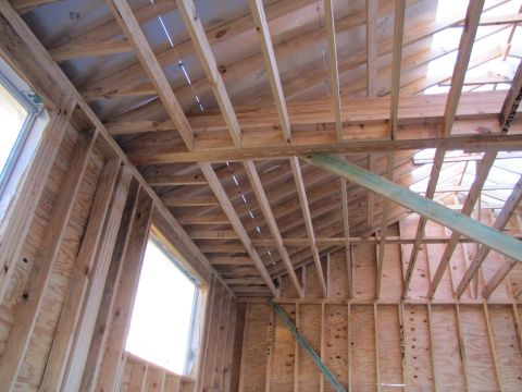 1995 Ford Bronco - The image shows the interior framing of a building under construction, with exposed wooden beams and plywood walls. A window opening is vis…