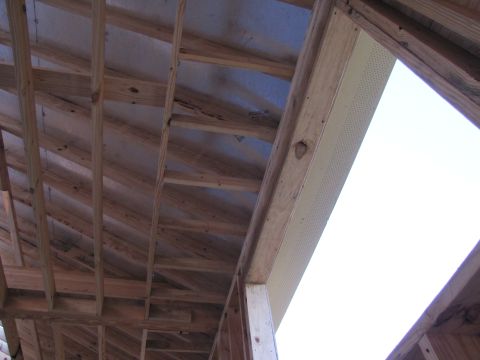 1995 Ford Bronco - The image shows the interior framing of a building under construction, with wooden beams and rafters visible. A large opening reveals a bri…