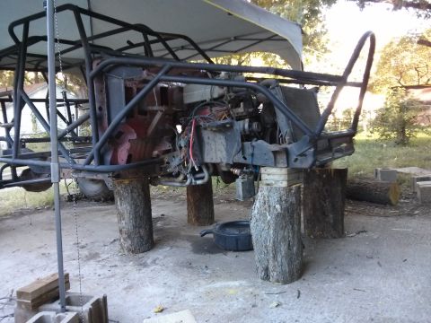 1986 Ford Bronco - A custom-built tube chassis vehicle, possibly a buggy or off-road project, is elevated on large tree stumps. The front end shows a radiator…