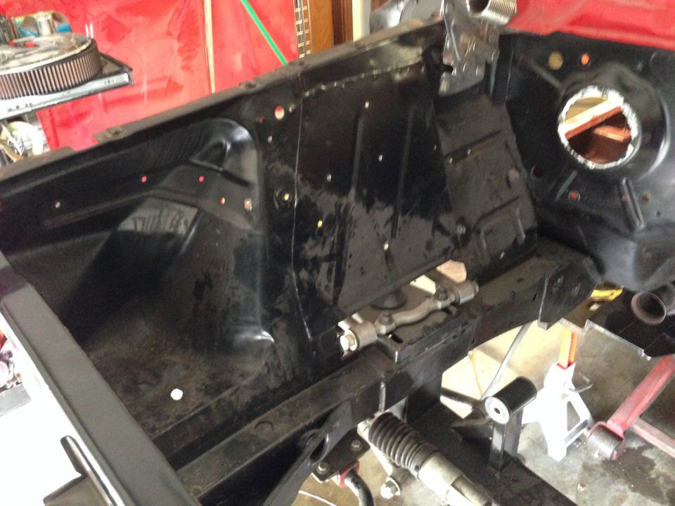 Black painted engine bay and chassis of a classic car.