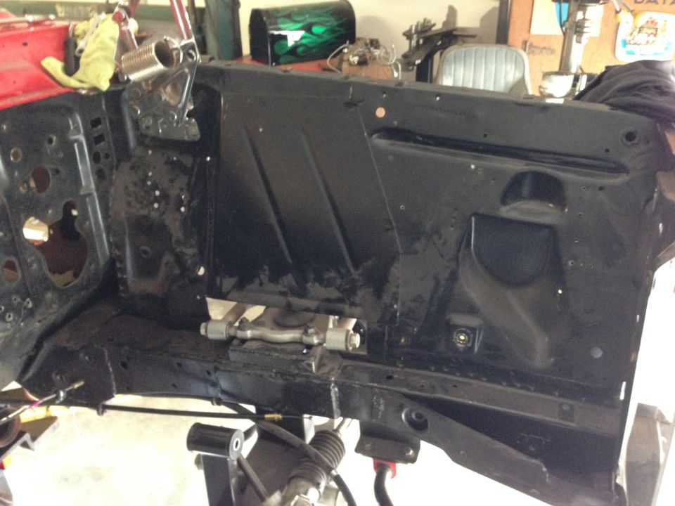 Black firewall and subframe of a classic car, with red fender visible.