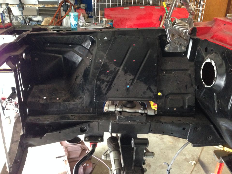 Black painted engine bay of a classic car with red and yellow paint marks.