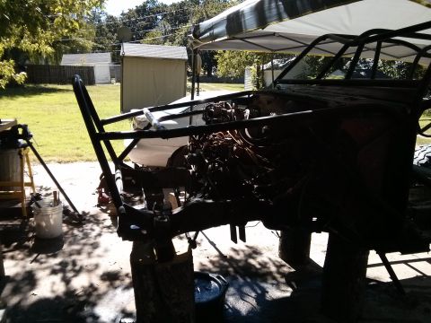 1986 Ford Bronco - A partially disassembled vehicle, likely a custom build or project, is shown outdoors under a canopy. The vehicle's frame and engine compon…