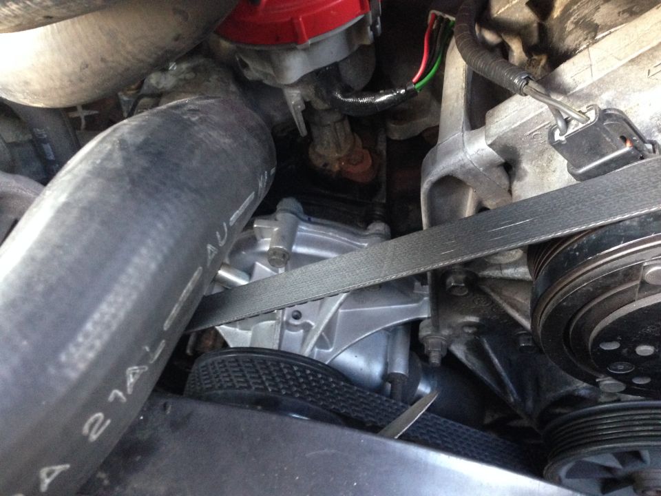 Engine bay view of a serpentine belt, AC compressor pulley, and accessories