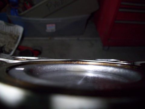 1995 Ford Probe - A close-up, low-angle shot of a metal gasket with a dark, circular recess, likely from an engine. The gasket shows signs of wear and a thin…