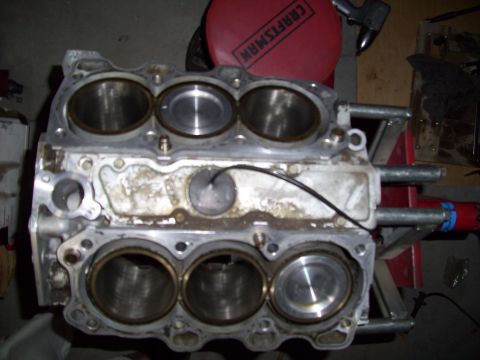 1995 Ford Probe - The image shows the top of an engine block with four cylinders visible. The engine block is silver and appears to be undergoing maintenance…