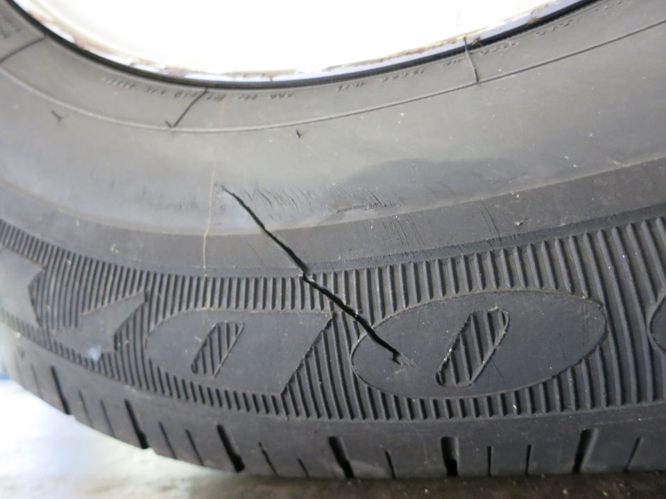 Close-up photo of a tire showing a crack or split in the sidewall and tread