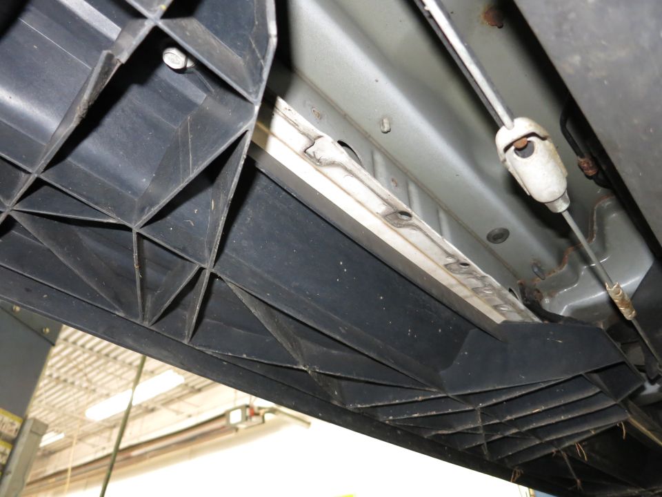 Underbody photo of a plastic running board, rocker rail and cable