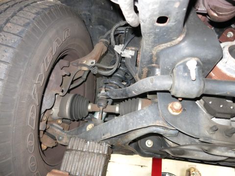 1991 Ford LTD Crown Victoria - Photograph of a vehicle's front suspension, CV axle and brake assembly, not a technical document.