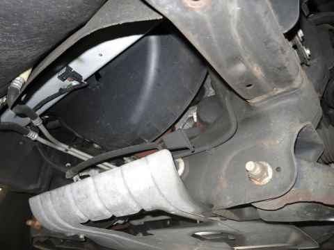 1991 Ford LTD Crown Victoria - Photograph of a vehicle's underside heat shield and exhaust routing, not a technical document.