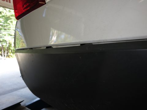 1991 Ford LTD Crown Victoria - Photograph of the rear corner of a white vehicle's bumper and body panel, not a technical document.