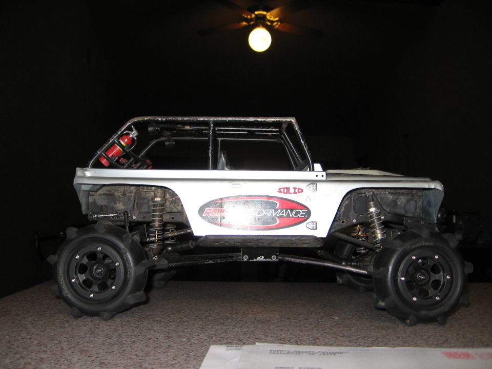 RC rock crawler with roll cage, off-road tires, and fire extinguisher, silver with red graphics.