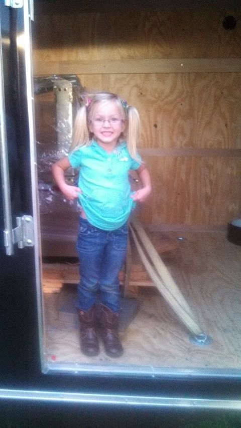 1979 Ford Bronco - A young girl with blonde pigtails and glasses stands inside a trailer, holding up her turquoise shirt.