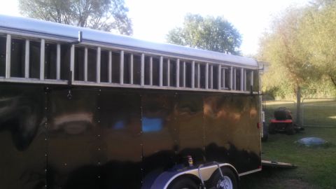 1979 Ford Bronco - A black trailer with a ladder secured to the roof is parked in a grassy area with trees in the background. A red riding lawn mower is visib…
