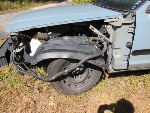 2001 Ford Crown Victoria - The front passenger side of a light blue 2001 Ford Crown Victoria is shown, with the fender removed and the wheel exposed. Wires and hoses…