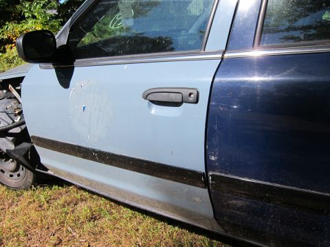 2001 Ford Crown Victoria - The side of a two-tone Ford Crown Victoria, with a light blue front door and a dark blue rear door, is shown parked on grass. The vehicle h…