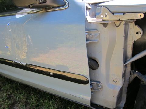 2001 Ford Crown Victoria - The driver's side door of a light blue sedan is open, revealing the interior door jamb and hinges. The lower portion of the door shows sign…