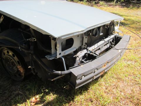 2001 Ford Crown Victoria - The front end of a light blue car is shown, with the hood open and the bumper removed, revealing the radiator and other engine components.…