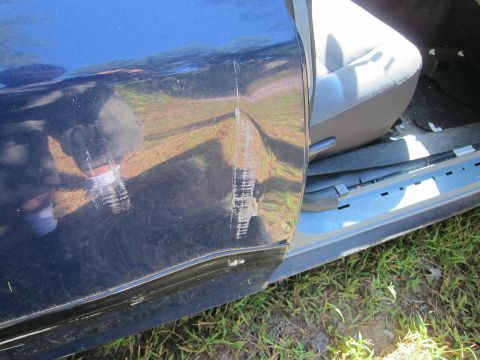 2001 Ford Crown Victoria - A close-up view of the exterior of a dark blue vehicle door, showing significant damage including deep scratches and a dent. The interior o…