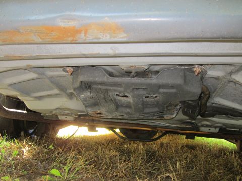 2001 Ford Crown Victoria - The underside of a vehicle, showing the exhaust system and a rusted metal component attached to the chassis. The vehicle appears to be a se…