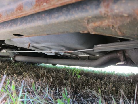 2001 Ford Crown Victoria - The underside of a vehicle showing the exhaust pipe and fuel tank. The vehicle appears to be resting on grass.