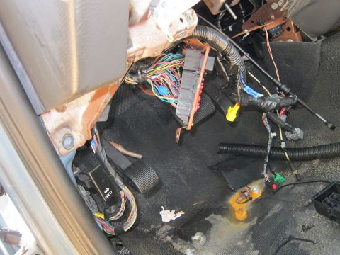 2001 Ford Crown Victoria - The interior of a vehicle shows a complex wiring harness and fuse box under the dashboard, with pedals visible on the floor. Rust is presen…