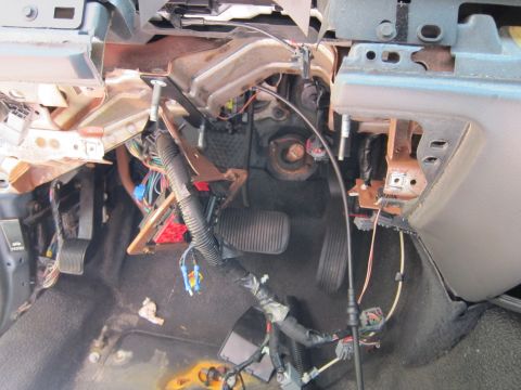 2001 Ford Crown Victoria - The interior of a vehicle's dashboard area shows exposed wiring, pedals, and parts of the steering column support structure. The area appea…