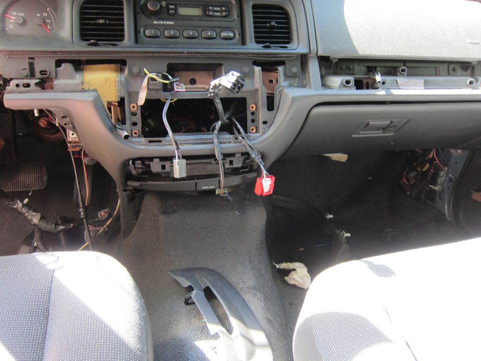 Disassembled car dashboard interior with exposed wires and components.