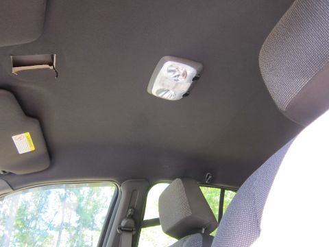 2001 Ford Crown Victoria - The interior of a car's headliner is shown, featuring a dome light and a sun visor with a warning sticker. The view looks upwards towards t…