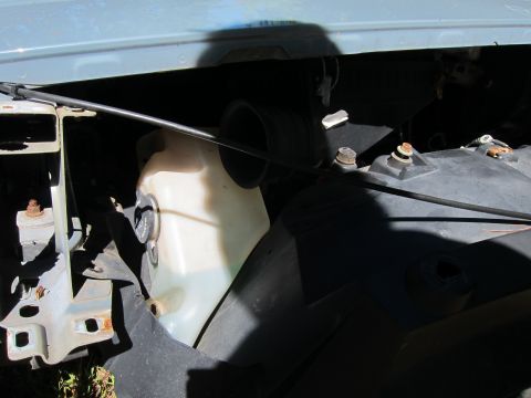2001 Ford Crown Victoria - A close-up view of the engine bay of a 2001 Ford Crown Victoria, showing the windshield washer fluid reservoir and part of the headlight as…