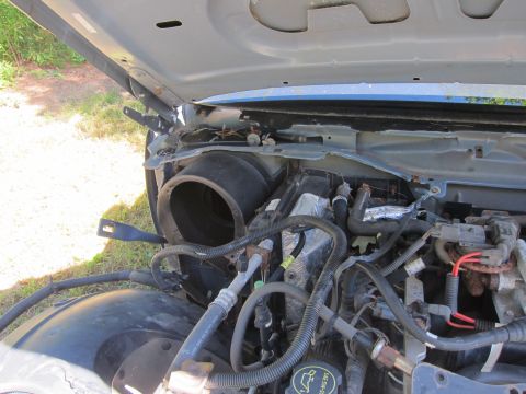 2001 Ford Crown Victoria - The open hood of a 2001 Ford Crown Victoria reveals the engine bay and HVAC components. Visible parts include the air intake duct, hoses, a…