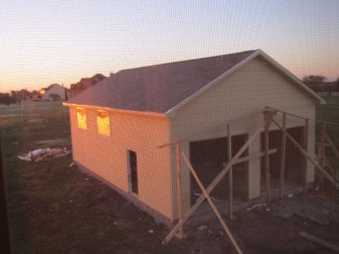 1995 Ford Bronco - A partially constructed garage building is shown at dusk with the sun setting in the background. The building has a light-colored exterior…