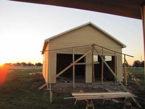 1995 Ford Bronco - A construction scene at sunset shows a partially built garage with wooden framing in front of the structure. The sun is setting on the left…