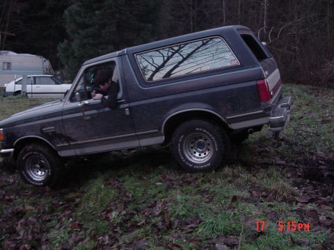 1987 Ford Bronco - 1987 Ford Bronco navigating rough terrain in a wooded area.