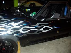 1993 Ford Mustang - A black car with flame decals is seen from the 3/4 front angle, with another vehicle visible behind it.