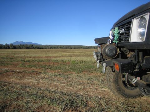 1987 Suzuki Samurai - 1987 Suzuki Samurai front end with a toy soldier on the grille, parked in a field.