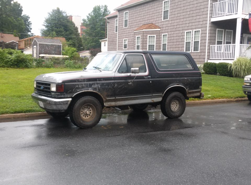 Black 1990 Ford Bronco parked on a wet street