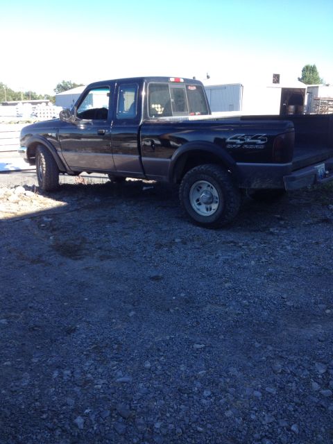 1995 Ford F-150 - A black pickup truck is parked on a gravel lot under a clear blue sky.