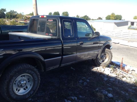 1995 Ford F-150 - This black pickup truck is viewed from the side, showing its toolbox and off-road tires.