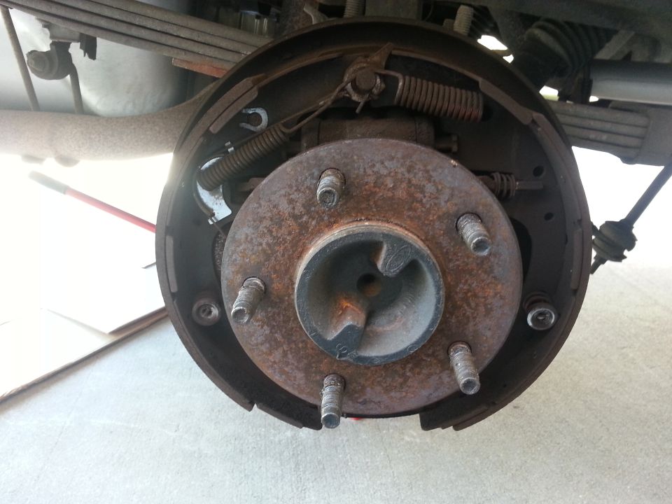 Close-up of a rusty rear drum brake assembly with springs and hardware