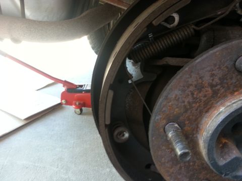 1994 Ford Bronco - A red hydraulic jack is positioned under the vehicle near the rear drum brake assembly.