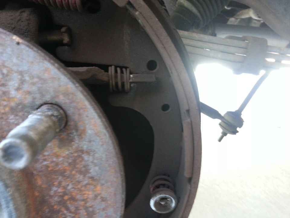 Drum brake assembly with rusty hub, brake shoe, springs, and linkage. Visible text: SUPERMOTORS.NET