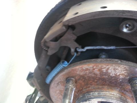 1994 Ford Bronco - Rear drum brake assembly with visible brake shoes, springs, and cable mechanism.