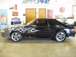1993 Ford Mustang - Side view of a black 1993 Ford Mustang coupe adorned with flame graphics and custom wheels.