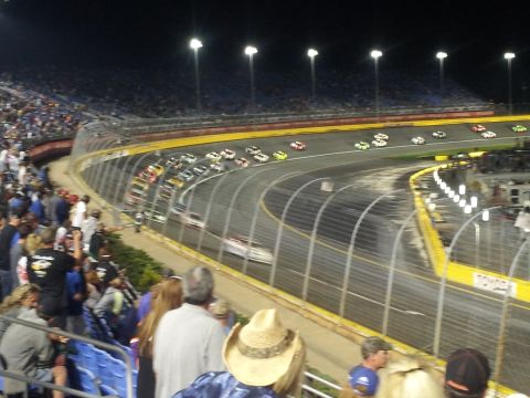 1986 Ford Bronco - A nighttime race is underway with multiple cars on the track and fans watching from the stands.